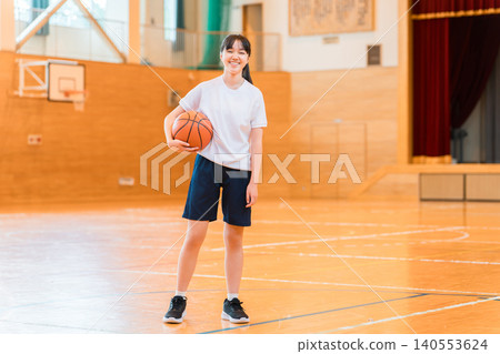 Female junior high school students and high school students wearing gym clothes holding basketballs in a gymnasium 140553624