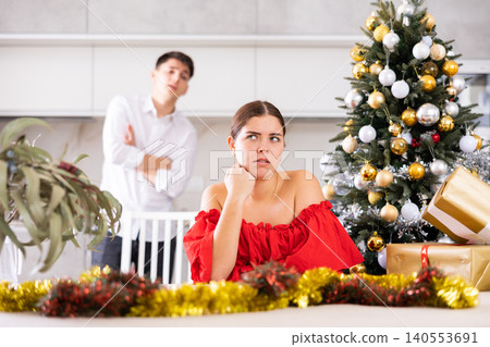 Portrait of married couple offended at each other after quarrel during the Christmas celebration, sitting at armchair in an apartment Portrait of married couple offended at each other after quarrel during the Christmas celebration, sitting at armchair in an apartment 140553691