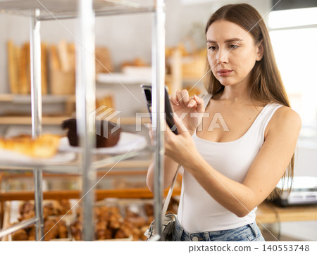 Young woman scanning pastry with her phone in bakery Young woman scanning pastry with her phone in bakery 140553748