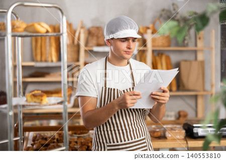 Frustrated male owner of bakery reads documents and reflects, makes decisions. Frustrated male owner of bakery reads documents and reflects, makes decisions. 140553810