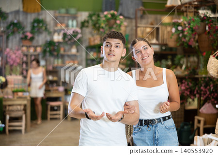 Married couple look for something in room garden furniture store, searching for item to complete patio. Woman with husband buyers looks around in showroom Married couple look for something in room garden furniture store, searching for item to complete patio. Woman with husband buyers looks around in showroom 140553920