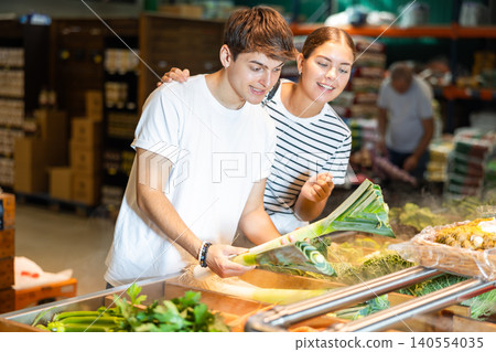 Young woman and young guy choosing leeks in grocery store 140554035