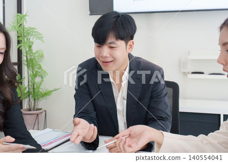 Asian business team collaborating in modern office meeting for corporate strategy discussion three people 140554041
