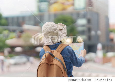 Asian woman tourist looking at map outdoors for travel navigation and city exploration tourism Asian woman tourist looking at map outdoors for travel navigation and city exploration tourism 140554164
