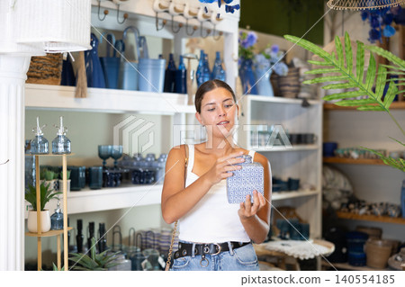 Young girl chooses beautiful wine decanter in hardware store 140554185