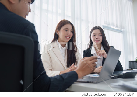 Asian business team collaborating on a presentation with laptop in modern office meeting teamwork discussion Asian business team collaborating on a presentation with laptop in modern office meeting teamwork discussion 140554197