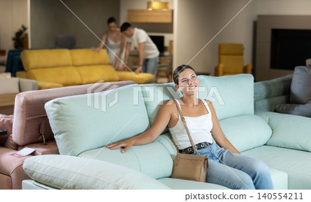 Young woman chooses sofa in store Young woman chooses sofa in store 140554211
