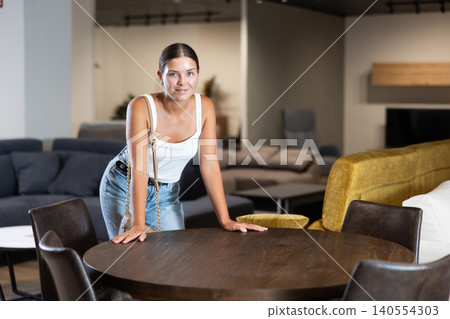 Woman visiting furnishing store in search of comfortable dining table for home 140554303