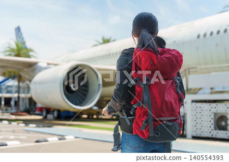 Asian woman with backpack looking at airplane at airport Asian woman with backpack looking at airplane at airport 140554393