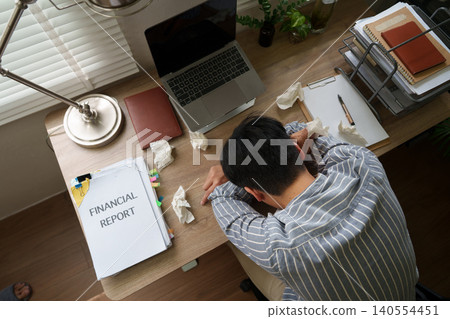 Asian man suffering burnout and exhaustion with financial report in home office 140554451