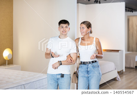 Young couple choosing convenient mattress in furniture shop Young couple choosing convenient mattress in furniture shop 140554567