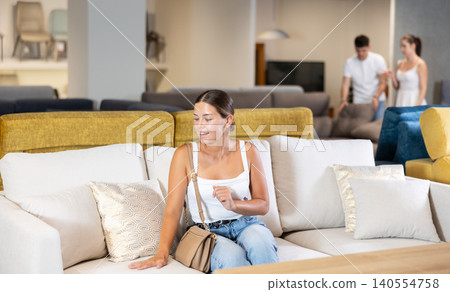 Young girl choosing convenient sofa in furniture shop Young girl choosing convenient sofa in furniture shop 140554758