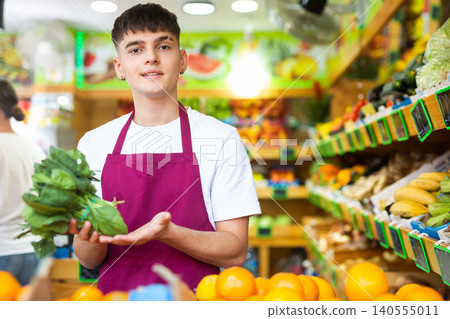 Portrait of a guy seller, holding a bunch of greenery in his hands Portrait of a guy seller, holding a bunch of greenery in his hands 140555011