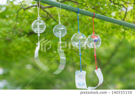 Glass wind chimes swaying under green maples Glass wind chimes swaying under green maples 140555159