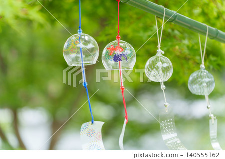 Glass wind chimes swaying under green maples Glass wind chimes swaying under green maples 140555162