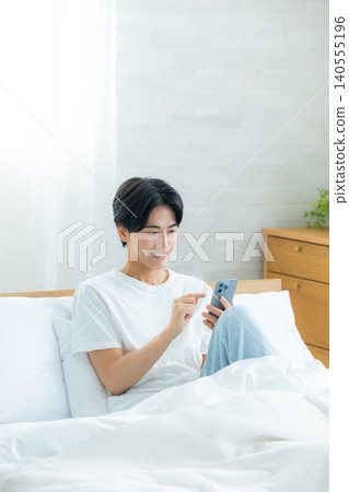 Men watching smartphones in bed Men watching smartphones in bed 140555196