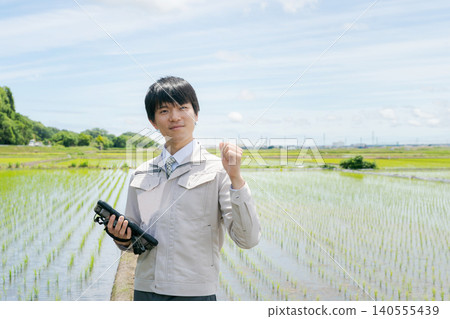 A man stands in a rice field and makes a triumphant gesture. A man stands in a rice field and makes a triumphant gesture. 140555439
