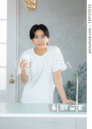 一名男子正在用玻璃杯喝水。 一名男子正在用玻璃杯喝水。 140555532