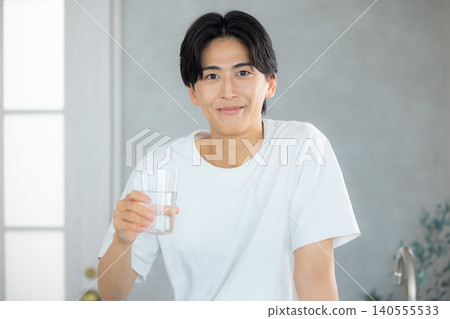 一名男子正在用玻璃杯喝水。 一名男子正在用玻璃杯喝水。 140555533
