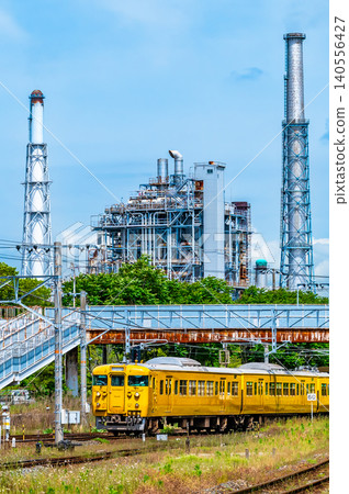一列 115 系列列車行駛在山陽本線上，背景是一座煉油廠，靠近櫛濱站。 140556427