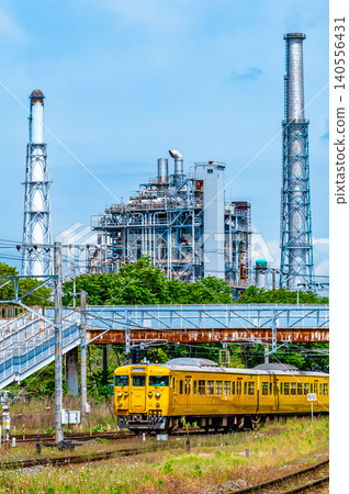 一列 115 系列列車行駛在山陽本線上，背景是一座煉油廠，靠近櫛濱站。 140556431