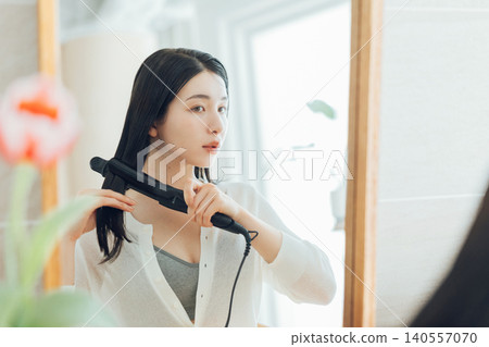 Women using hair straighteners Women using hair straighteners 140557070