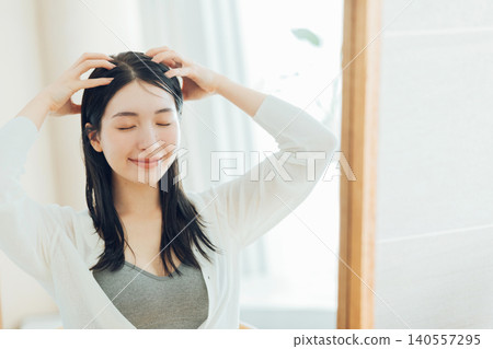 A young woman giving a scalp massage. A young woman giving a scalp massage. 140557295