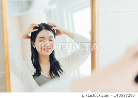 A young woman giving a scalp massage. 140557296