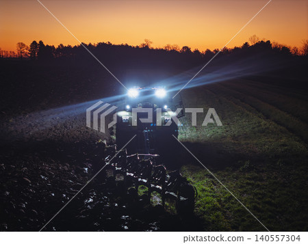 close up Tractor Plowing Field at night with headlights close up Tractor Plowing Field at night with headlights 140557304