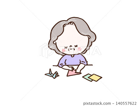 A senior woman with a gentle smile folds origami paper in her hands (hobby: brain training). A senior woman with a gentle smile folds origami paper in her hands (hobby: brain training). 140557622