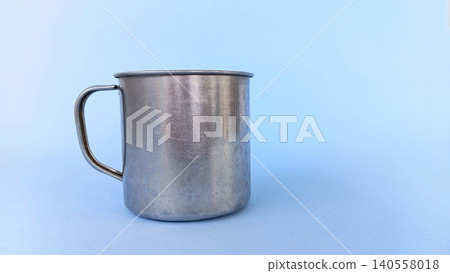 Empty stainless steel cup or mug on blue background. Empty stainless steel cup or mug on blue background. 140558018