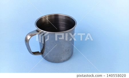 Empty stainless steel cup or mug on blue background. Empty stainless steel cup or mug on blue background. 140558020