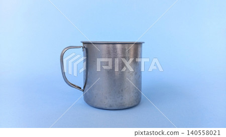 Empty stainless steel cup or mug on blue background. Empty stainless steel cup or mug on blue background. 140558021