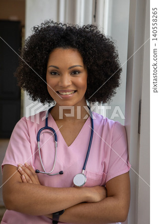 African american woman nurse leaning against corridor in pink scrubs with stethoscope and smiling African american woman nurse leaning against corridor in pink scrubs with stethoscope and smiling 140558265