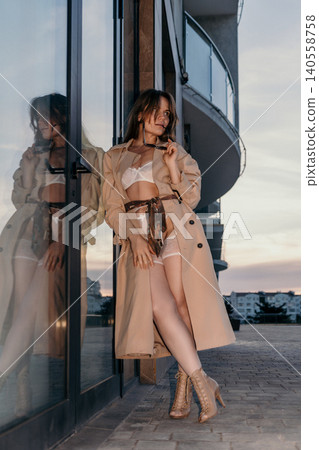 Trench coat lingerie woman leaning against glass door on terrace during sunset showcasing seductive fashion and urban elegance Trench coat lingerie woman leaning against glass door on terrace during sunset showcasing seductive fashion and urban elegance 140558758