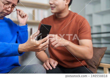 East Asian man teaching senior man how to use smartphone for digital learning 140558818