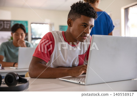 African american and asian teenage students typing on laptops at class 140558917