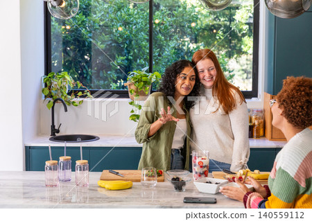 Diverse female friends mixing berries, pouring infused water at marble kitchen island counter Diverse female friends mixing berries, pouring infused water at marble kitchen island counter 140559112