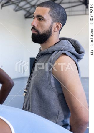 Man coaching on basketball court at gym wearing sleeveless hoodie and whistle, copy space Man coaching on basketball court at gym wearing sleeveless hoodie and whistle, copy space 140559218