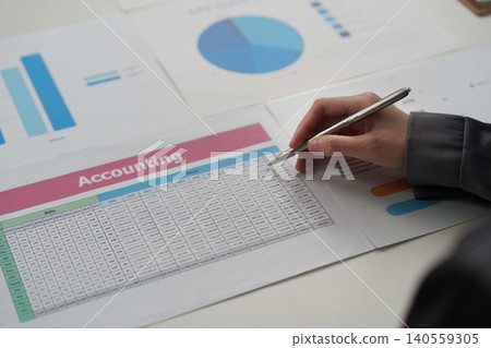 Asian woman in 20s writing notes on accounting document in office Asian woman in 20s writing notes on accounting document in office 140559305