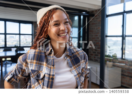 African American woman standing near windows in loft office wearing plaid flannel shirt African American woman standing near windows in loft office wearing plaid flannel shirt 140559338