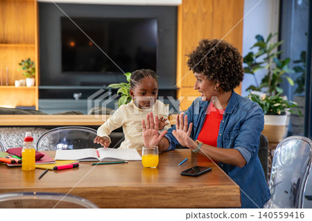 African american mother with preschool daughter teaching counting game at home at table African american mother with preschool daughter teaching counting game at home at table 140559416