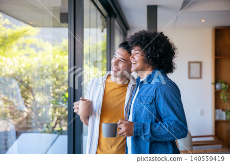 Two men holding ceramic mugs and gazing through floor-to-ceiling glass door in modern living room Two men holding ceramic mugs and gazing through floor-to-ceiling glass door in modern living room 140559419