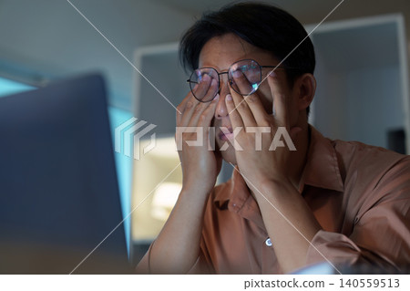 Asian man in 30s with eye strain working on laptop, fatigue 140559513