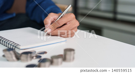 Asian man writing in notebook, planning savings and personal finance 140559515