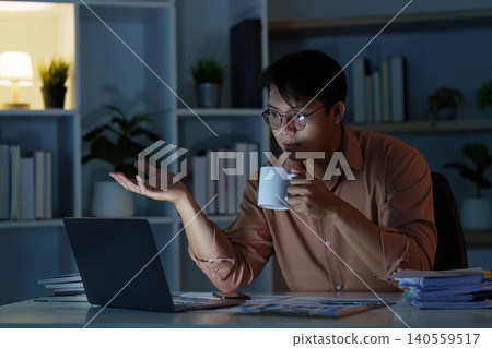 Asian man on video call, remote communication from home office at night 140559517