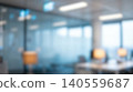 Blurred modern office workspace interior featuring empty desks illuminated by warm lamps alongside glass partitions creating professional business company environment background 140559687