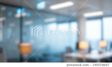 Blurred modern office workspace interior featuring empty desks illuminated by warm lamps alongside glass partitions creating professional business company environment background 140559687
