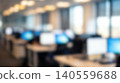 Blurred spacious open plan office interior featuring multiple computer monitors resting across empty desks creating modern professional corporate workplace business technology background 140559688