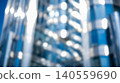 Blurred modern blue glass skyscraper featuring metallic exterior elements reflecting bright sunlight creating abstract corporate business finance city building background 140559690